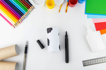 New year decoration. DIY and kids creativity concept. Step by step instructions: make a cow from a roll of toilet paper and paper. Step 7 draw spots with a black felt-tip pen.