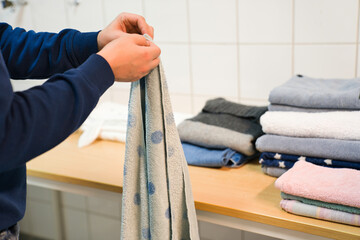 ランドリールームで男性が洗濯物を畳むシーン