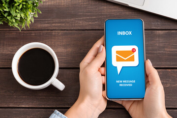 Flat lay of unrecognizable young woman checking her inbox for incoming email messages at desk during coffee break