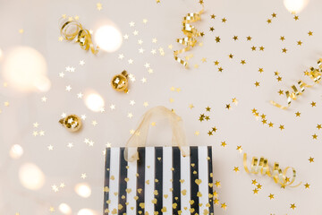 Festive gold background. Shining stars confetti, party streamers and decoration, holiday package on beige and Set Sail Champagne. Christmas. Wedding. Birthday. Flat lay, top view, copy space.