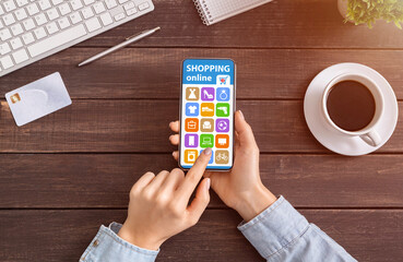 Naklejka na ściany i meble Female Customer Shopping Online With Smartphone Sitting At Desk Indoors