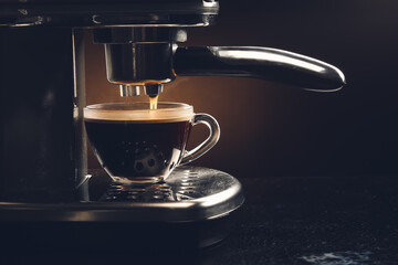 Modern coffee machine with cup of hot beverage on dark background, closeup