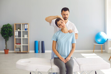 Professional chiropractor doing neck massage to young woman in modern medical office