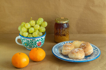 Still life with some traditional Spanish cakes, grapes, tangerines and a pot of honey presented in traditional hand-painted ceramic.