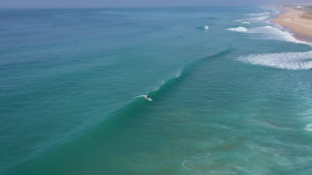Aerial drone footage of surfes riding on a long beautiful wave in the atlantic coast od Cadiz, Spain