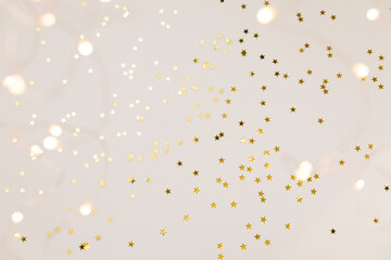 Festive gold background. Shining stars confetti and fairy lights on beige and Set Sail Champagne background. Christmas. Wedding. Birthday. Flat lay, top view, copy space - obrazy, fototapety, plakaty