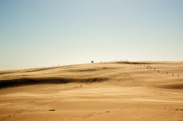 Krajobraz pustynny błękitne niebo i ruchome piaski z sylwetką idącego człowieka w pięknym świetle zachodzącego słońca	
 - obrazy, fototapety, plakaty