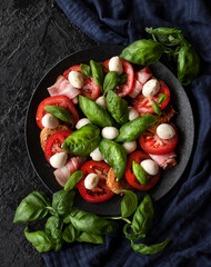 Italian Caprese salad with sliced tomatoes, mozzarella cheese, fried steaks, Basil, olive oil. Rustic style. The view from the top.