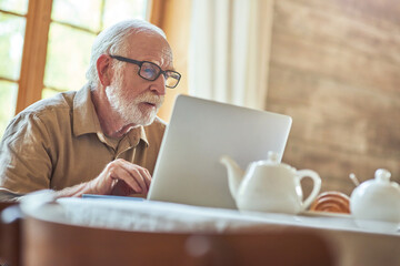 Fototapeta premium Gray-haired senior man using computer while typing