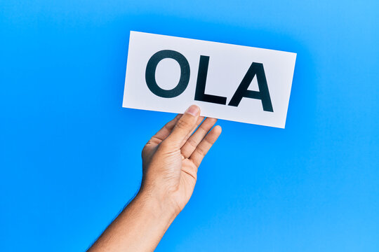 Hand of hispanic man holding ola word paper over isolated blue background.