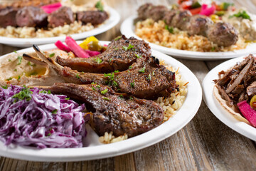 A view of several Mediterranean entrees on a table, featuring lamb chops.