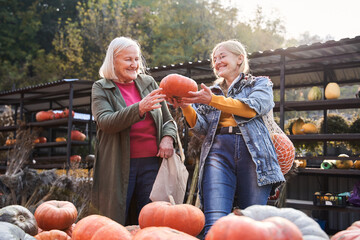 Mother and daughter holding big orange pumpkin