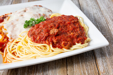 A view of a plate of spaghetti with meat sauce and a chicken parmigiana.
