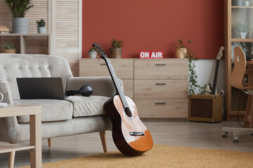 Background image of modern room interior with music instruments and On air sign, focus on guitar in...