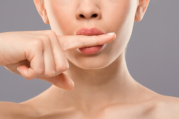 Cropped of woman holding finger between her lips