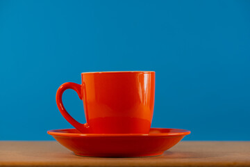 red cup with coffee stands on a wooden table.