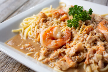 A view of a rustic plate of seafood spaghetti, featuring shrimp and clam meat.