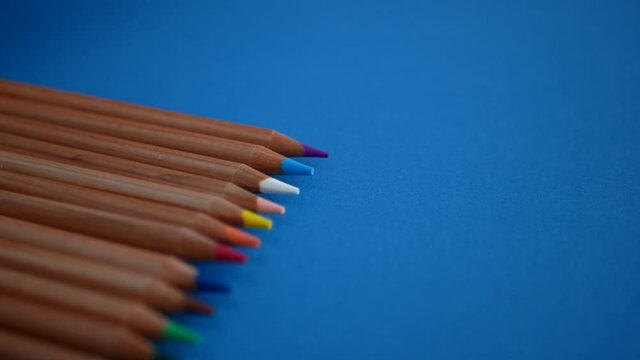Multicolored pencils rolling over the blue surface, Tools for different creative projects 