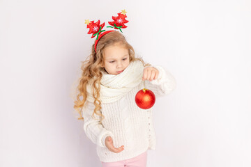 baby girl holding a red Christmas ball on a white isolated background, space for text
