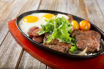 A view of a skillet plate of steak and eggs.