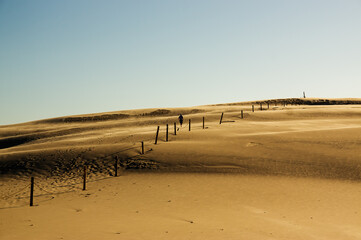 Krajobraz pustynny błękitne niebo i ruchome piaski z sylwetką idącego człowieka w pięknym świetle zachodzącego słońca   © Monika