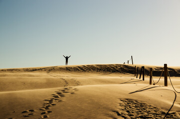 Krajobraz pustynny błękitne niebo i ruchome piaski z sylwetką idącego człowieka w pięknym...