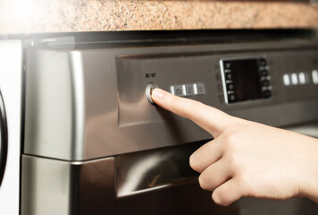 Young woman pushing the buttons on the dishwasher