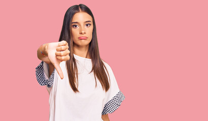 Young hispanic woman wearing casual clothes looking unhappy and angry showing rejection and negative with thumbs down gesture. bad expression.