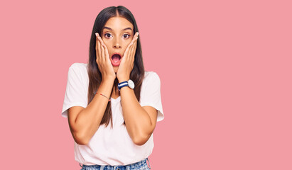 Young hispanic woman wearing casual white tshirt afraid and shocked, surprise and amazed expression...
