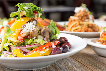 A view of a Greek salad plate, next to several other Mediterranean dishes.