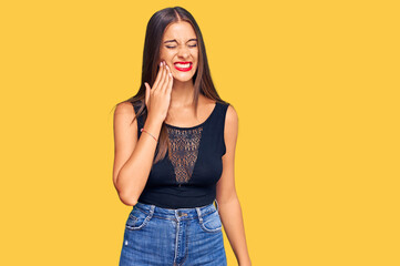 Young hispanic woman wearing casual clothes touching mouth with hand with painful expression because of toothache or dental illness on teeth. dentist