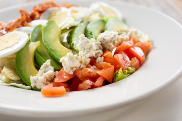 A closeup view of a cobb salad bowl, in a restaurant or kitchen setting.