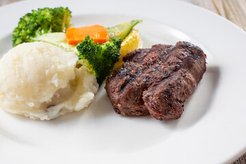 A view of a sirloin steak dinner, in a restaurant or kitchen setting.