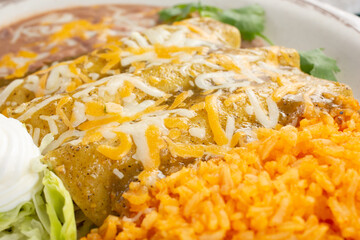 A view of a plate of enchiladas with green sauce, in a restaurant or kitchen setting.