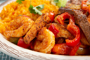 A closeup view of a meat fajitas plate, featuring shrimp, carne asada and chicken.