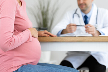 Unrecognizable male doctor consulting young pregnant woman