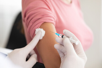 Male doctor doing vaccination to young woman - obrazy, fototapety, plakaty