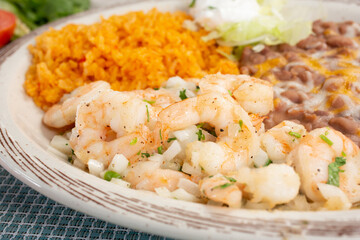 A view of a plate of garlic shrimp, in a restaurant or kitchen setting.