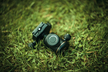 Black tripod head on green grass