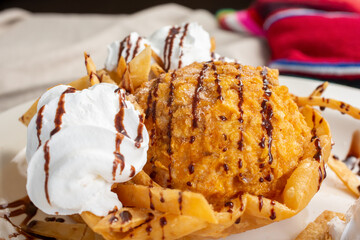 A view of a plate of deep fried ice cream, in a restaurant or kitchen setting.