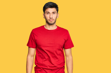 Young handsome man wearing casual red tshirt looking sleepy and tired, exhausted for fatigue and hangover, lazy eyes in the morning.