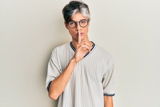 Young hispanic man wearing casual clothes and glasses asking to be quiet with finger on lips. silence and secret concept.