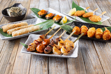 A view of a several appetizer plates, featuring yakitori.