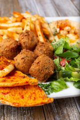 A view of a falafel plate, featuring hummus, french fries and pita bread.