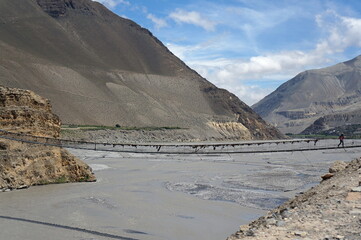 The Kali Gandaki River, with a suspension bridge across it, against the backdrop of the Himalayan...