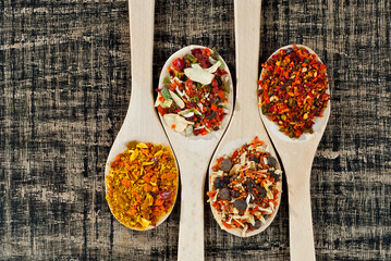 A mixture of various spices in a wooden spoon. Spices and seasonings on an old shabby board. Mix on a pile close up. Place for text and copy space near the spoon.