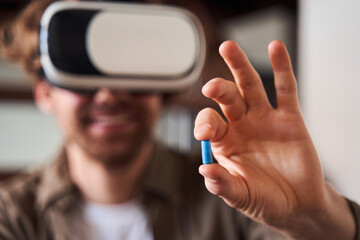 Fototapeta premium Man holding a blue pill at his fingers