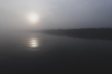 Fototapeta premium Dark, foggy river early in the morning during sunrise