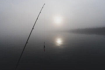 Fishing pole and lure on dark, foggy river in Alaska