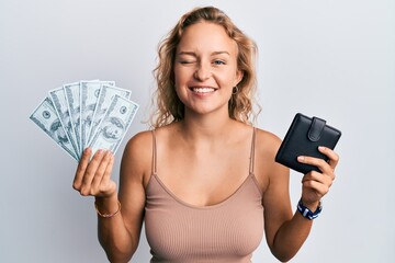 Beautiful caucasian woman holding wallet and dollars winking looking at the camera with sexy...